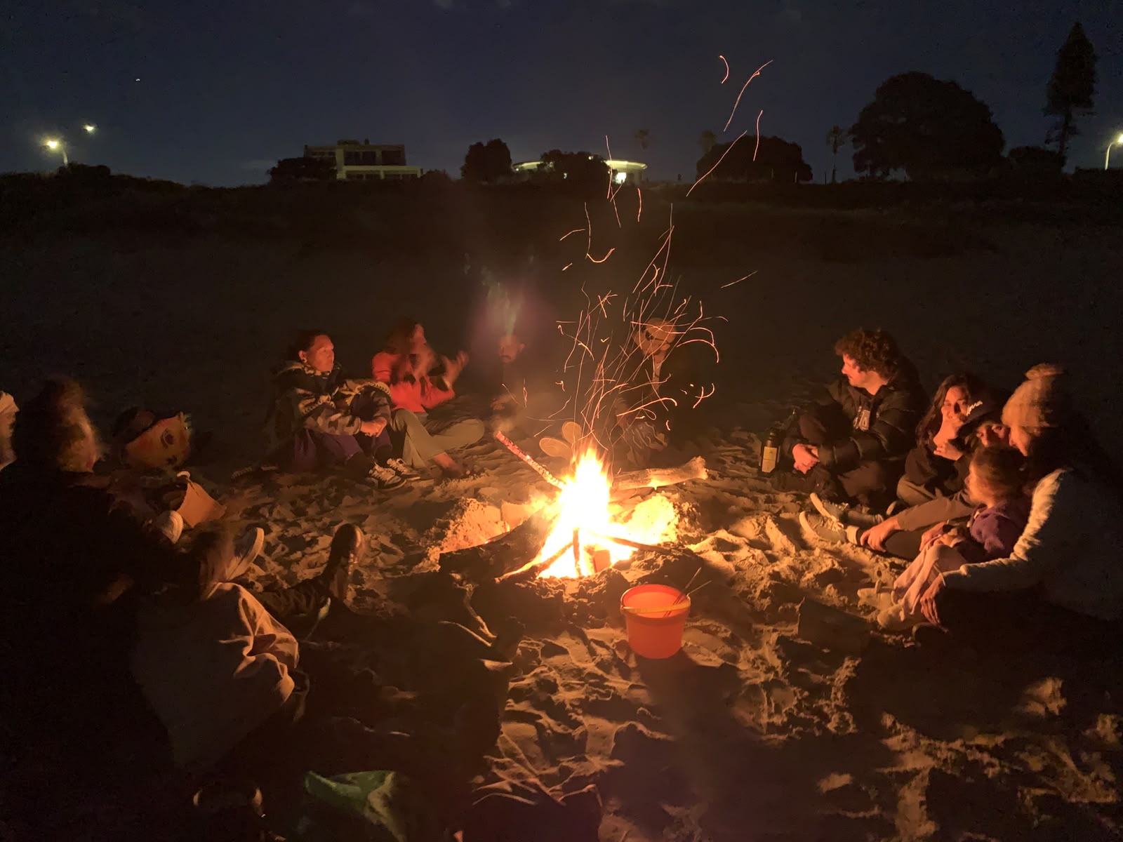 Community gathered around a fire on the beach